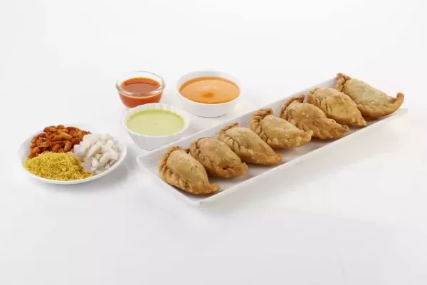 gujarati farsan spicy ghughra with veg. stuffing.spicy deep-fried dumpling made with suji.garnish with onion, shev, masala sing ,with green & red chatni.