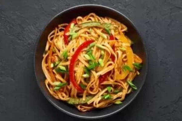 Vegetarian Schezwan Noodles or Vegetable Hakka Noodles or Chow Mein in black bowl at dark background. Schezwan Noodles is indo-chinese cuisine hot dish with udon noodles, vegetables and chilli sauce