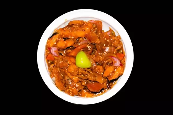 honey chilli potatoes in a spicy sauce, sesame seeds and green onions close-up, horizontal top view from above, isolated on black