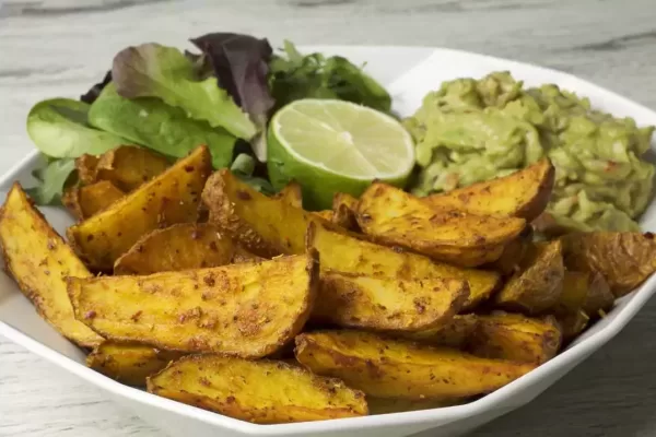 Spicy potato wedges with guacamole, green salad and lime