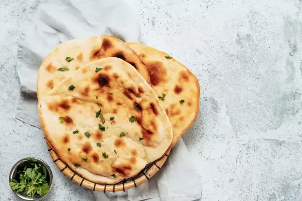 Fresh naan bread on gray cement background with copy space. Top view of several perfect naan flatbreads