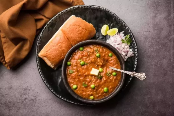 Mumbai Style Pav bhaji is a fast food dish from India, consists of a thick vegetable curry served with a soft bread roll, served in a plate